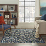 Living room scene with the Nourison Caribbean Navy Contemporary Area Rug, sofa, chair, and cityscape view.
