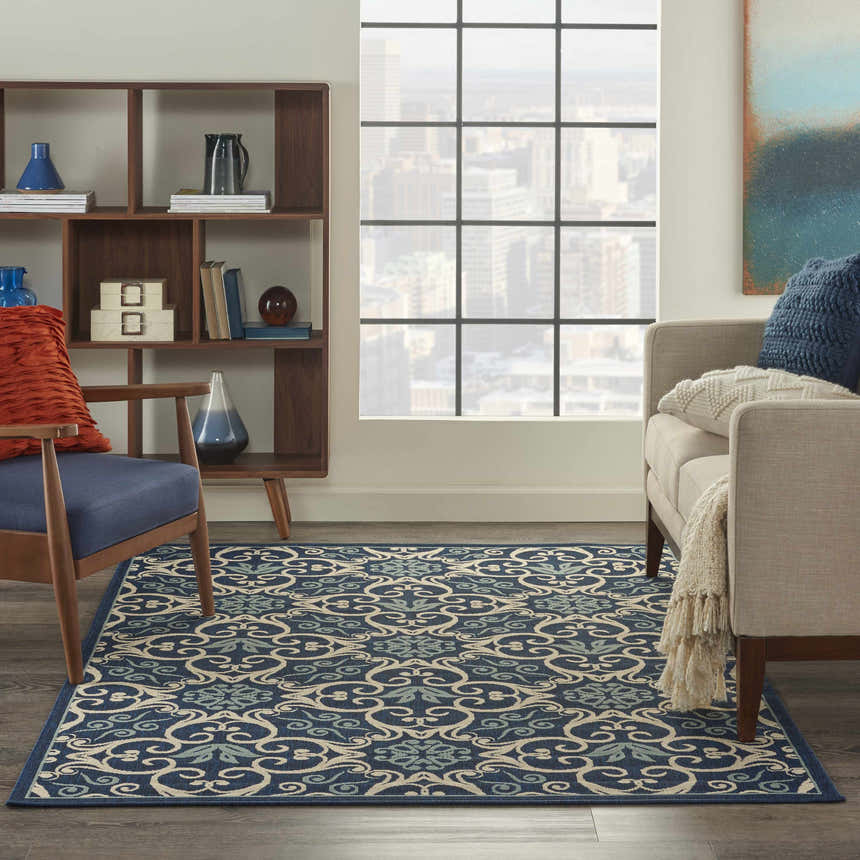 Living room scene with the Nourison Caribbean Navy Contemporary Area Rug, sofa, chair, and cityscape view.