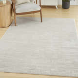 Living room scene with a Nourison Dew Beige rug, light wood floors, chair, and modern cabinet.