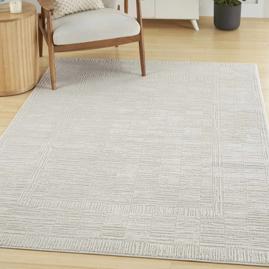 Living room scene with a Nourison Dew Beige rug, light wood floors, chair, and modern cabinet.