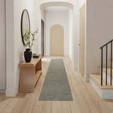 Farmhouse hallway with Nourison Natural Jute Sage runner rug, wood floors, console table, and arched doorway.