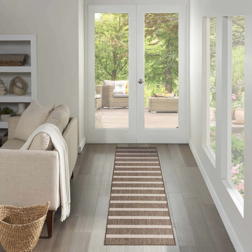 Entryway with a Nourison Positano Natural Ivory rug runner, light wood floors, and a view of an outdoor patio.