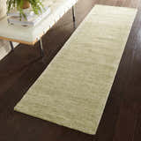 Hallway scene with a Nourison Weston Citron runner rug on dark wood floors, next to a white leather bench.