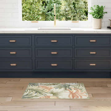 Kitchen scene with Nourison Aloha Ivory Green rug, navy cabinets, wood floors, and a bright window.