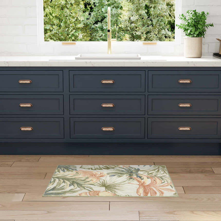 Kitchen scene with Nourison Aloha Ivory Green rug, navy cabinets, wood floors, and a bright window.