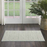 Farmhouse style entryway with Nourison Jubilant Ivory Green rug, dark wood floors, white doors, and a potted palm.