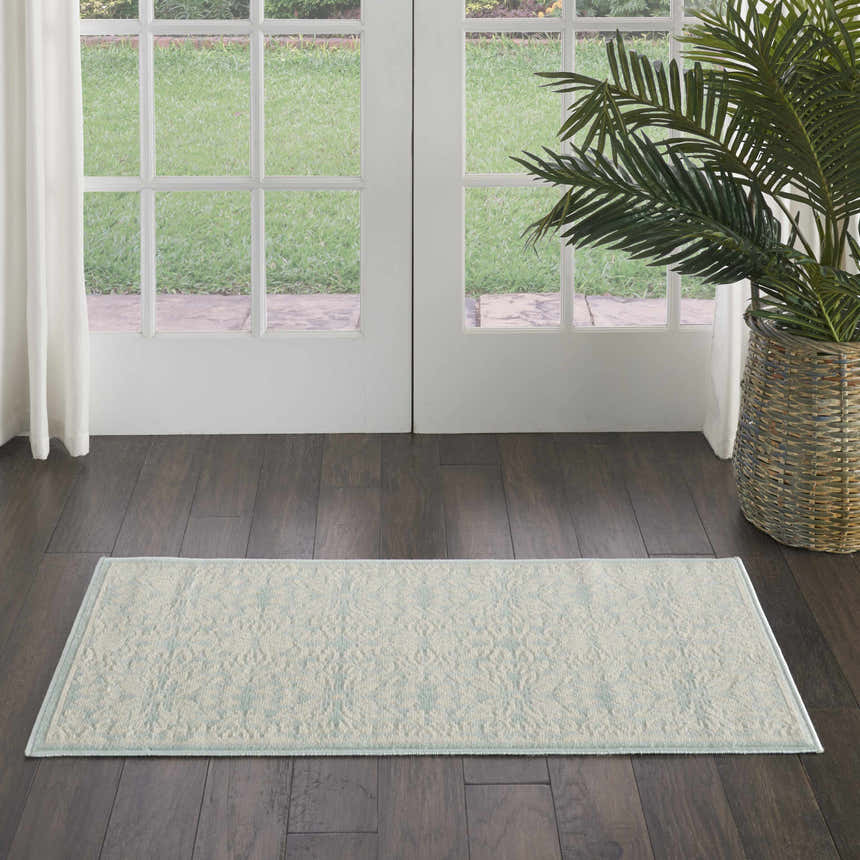 Farmhouse style entryway with Nourison Jubilant Ivory Green rug, dark wood floors, white doors, and a potted palm.