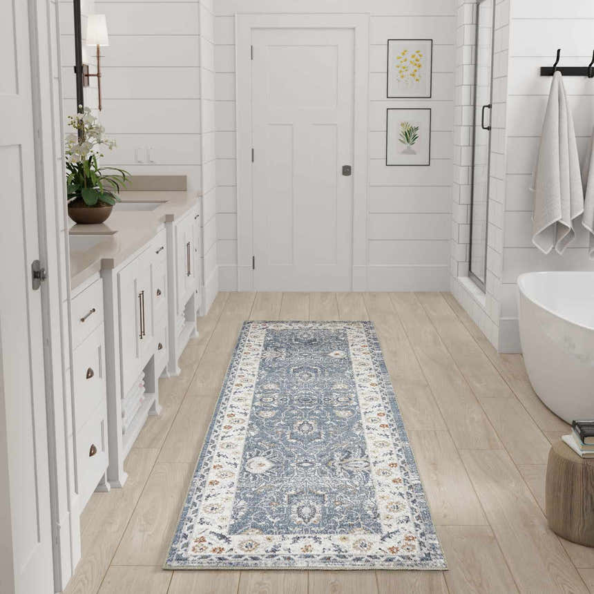 Bathroom scene with a Nourison Astra Blue Vintage runner rug, white cabinets, and light wood floors.