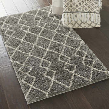 Close-up of a Nourison Martil Silver Gray Moroccan shag rug with geometric pattern on dark wood floor.