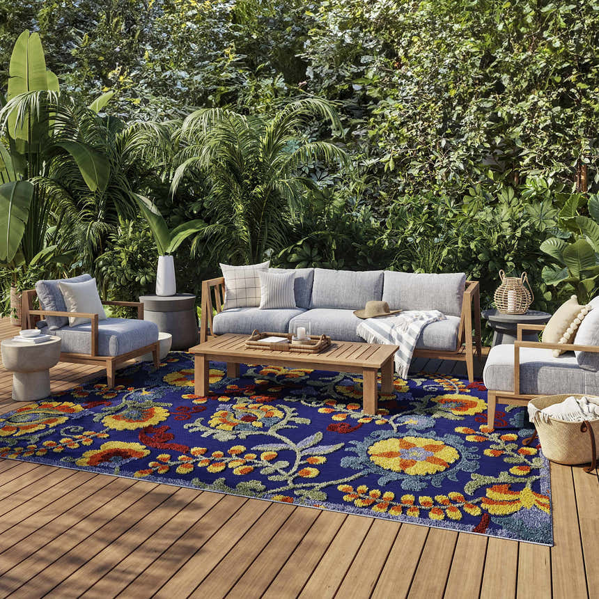 Outdoor patio scene with gray furniture on a Nourison Aloha Navy Multicolor area rug with a floral pattern.