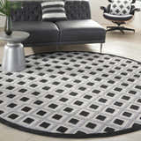 Modern living room with a round Nourison Aloha Black White area rug, black sofa, and stylish decor.
