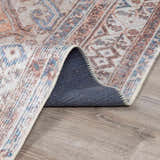 Close-up of Arncliffe Washable Area Rug showing its traditional pattern, colors (brown, blue, orange), and non-slip backing. Fold