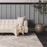 Living room scene with beige sofa on Akiye Area Rug. Geometric pattern in cream, beige, and gray. Modern style. Roomscene-Rectangle