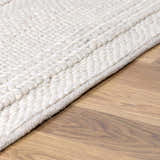 Close up of cream Alora Area Rug showing hand woven texture and wool blend on hardwood floor. Pile