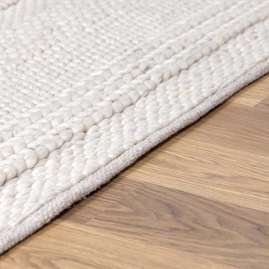 Close up of cream Alora Area Rug showing hand woven texture and wool blend on hardwood floor. Pile
