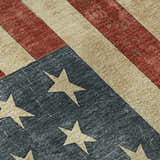 Close-up of the Americana AM1 Red Washable Area Rug. Features a distressed American flag design with beige stars and red stripes.