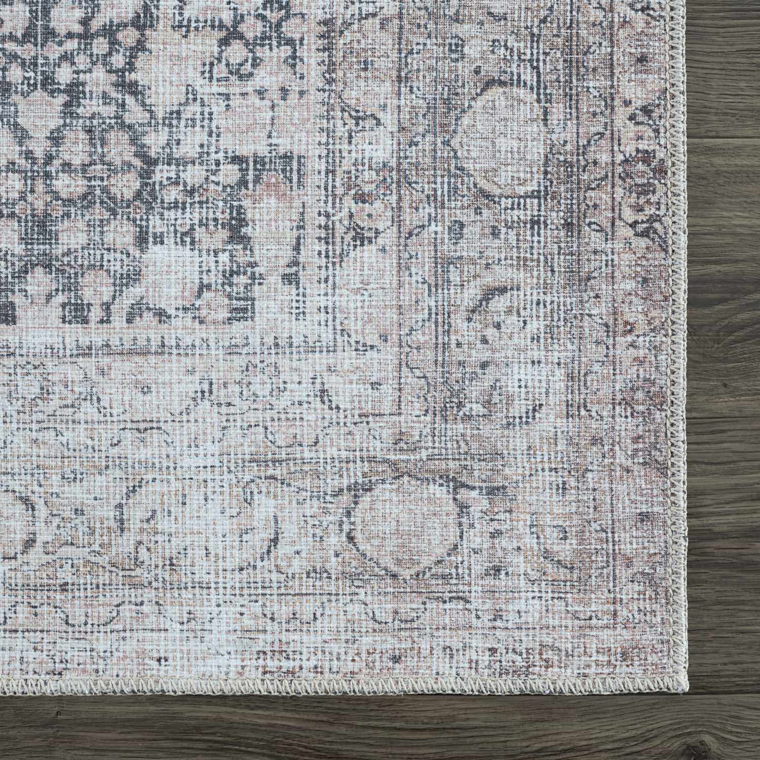 Close-up of the Hedda Boutique Washable Rug. Features a vintage, traditional pattern in dark gray, nutmeg, and light gray tones. Swatch