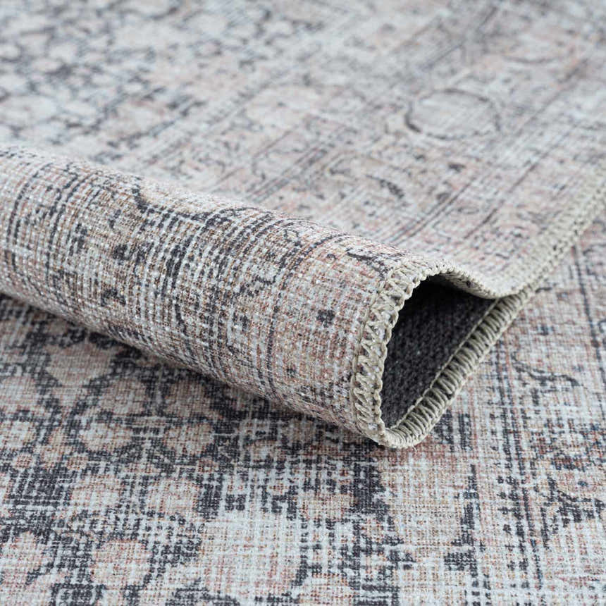 Close-up of the Hedda Boutique Washable Rug. Traditional design in dark gray, gray, and nutmeg colors. Soft chenille texture. Fold