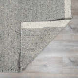 Close-up of the Basiao Area Rug. Hand woven charcoal, cream and gray wool and cotton blend with textured pile. Fold