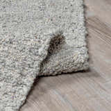 Close-up of the hand-woven Basiao Area Rug. Charcoal, cream, and gray wool and cotton texture. Contemporary style. Fold