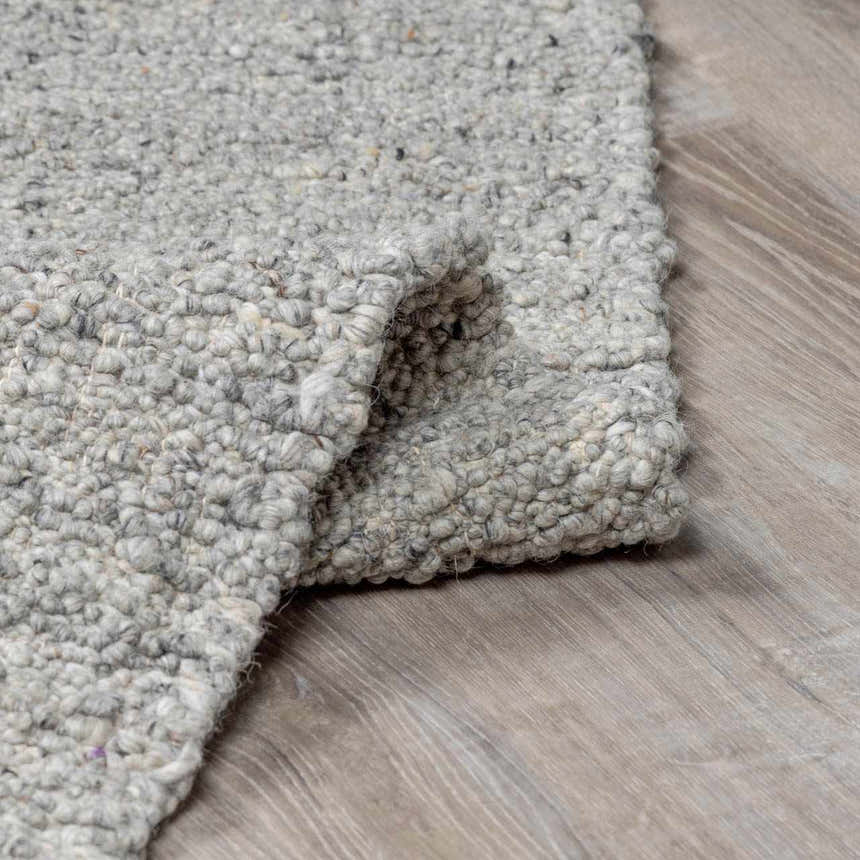 Close-up of the hand-woven Basiao Area Rug. Charcoal, cream, and gray wool and cotton texture. Contemporary style. Fold