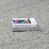 Close-up of the hand-woven Basiao Area Rug showing charcoal, cream, and gray tones. Stack of books on the rug. Styleshot