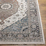 Close-up of the Baychester Area Rug showing its traditional design, cream, denim, and brown colors, and soft polyester texture. Front