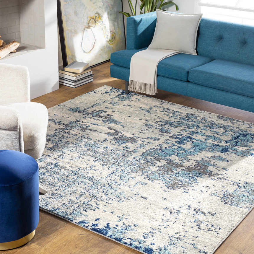 Living room scene with a Beverly Abstract Blue Area Rug, blue sofa, and cream armchair. Roomscene-Square