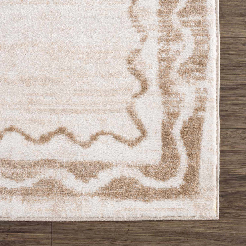 Close-up of the Beatus Washable Area Rug. Beige rug with a light brown geometric pattern and border on dark wood floor. Corner