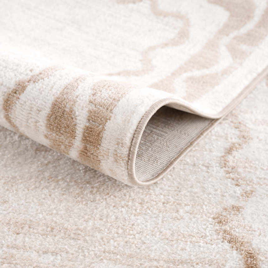 Close-up of the beige Beatus Washable Area Rug showing its geometric pattern, soft texture, and machine-woven construction. Fold