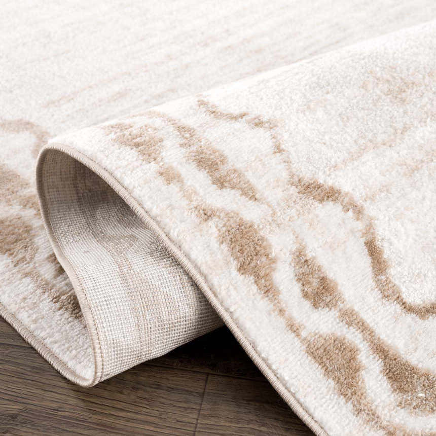 Close-up of the Beatus Washable Area Rug. Beige and light brown geometric pattern. Machine woven polyester rug. Fold