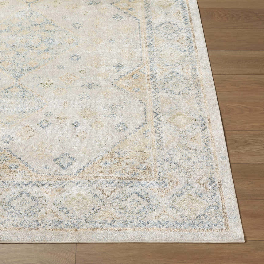 Close-up of the Bhavya Cream Washable Area Rug showing its beige, muted blue, and sage traditional pattern and soft texture. Front