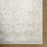 Close up of the Bhavya Cream Washable Area Rug, featuring a traditional beige, muted blue, and sage pattern. Corner