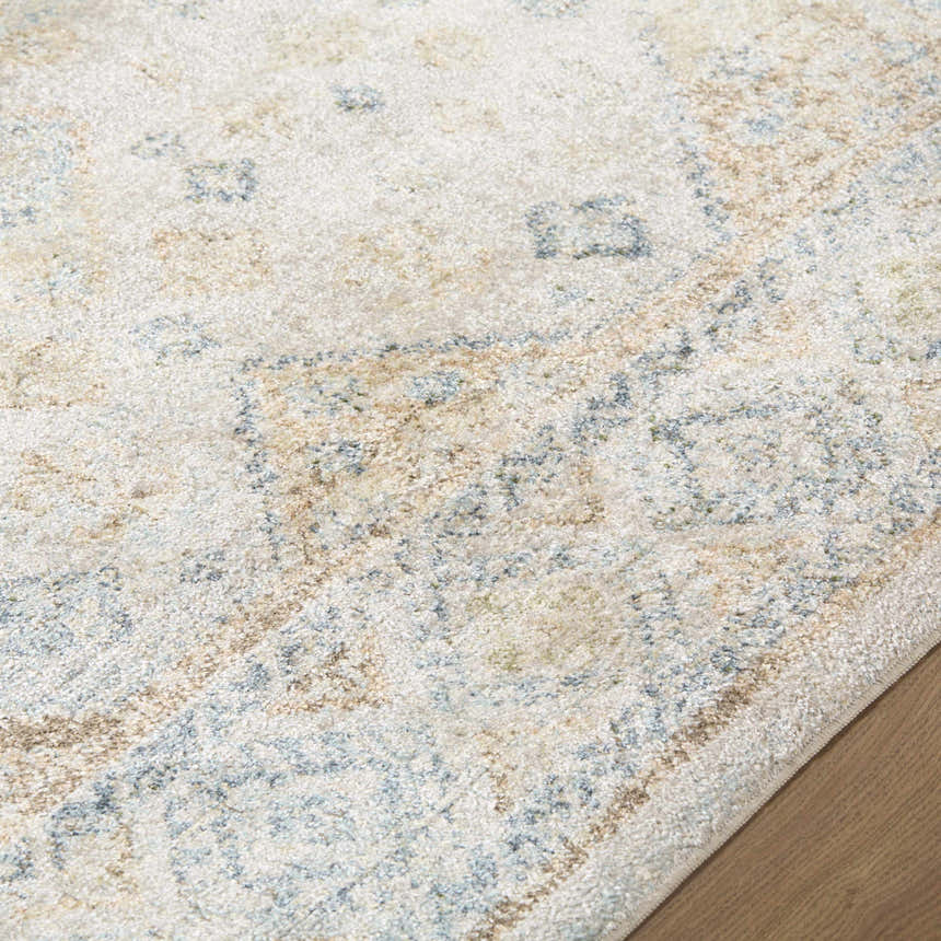Close-up of the Bhavya Cream Washable Area Rug. Beige rug with muted blue and sage traditional pattern. Soft texture. Texture