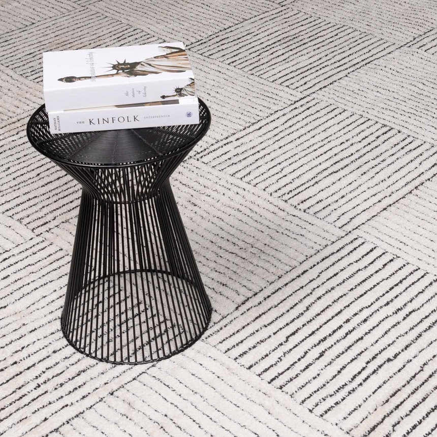 Close-up of Modern Scandi High Pile Architect I Area Rug in ivory and black, with geometric line pattern and black accent table. Styleshot