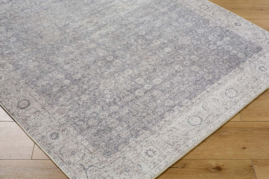 Close-up of the Spokane Machine Woven PNW Home x LIVABLISS area rug. Charcoal, dark brown, and off-white traditional pattern. Corner