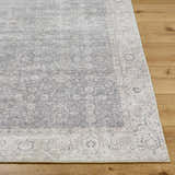 Close-up of the Spokane Machine Woven rug showing its charcoal, dark brown, and off-white traditional pattern and texture. Front