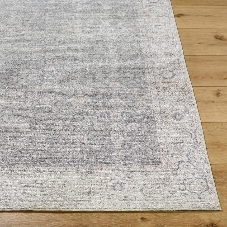 Close-up of the Spokane Machine Woven rug showing its charcoal, dark brown, and off-white traditional pattern and texture. Front