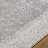 Close-up of the Spokane Machine Woven rug. Features a traditional pattern in charcoal, dark brown, and off-white. Texture