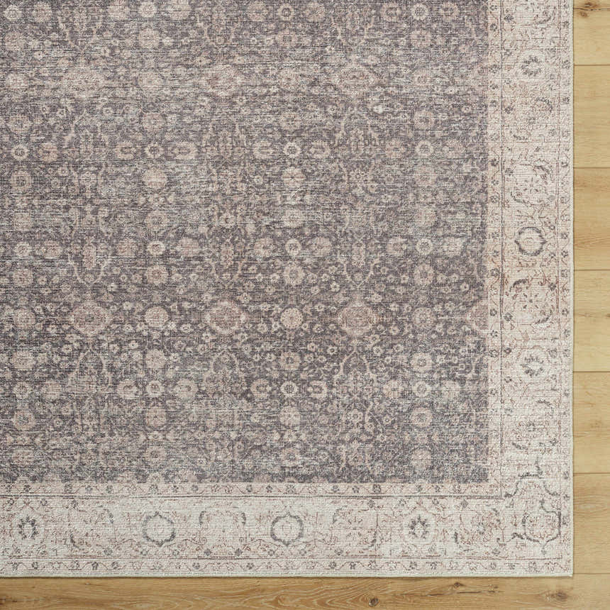 Close-up of the Spokane Machine Woven rug. Charcoal, ivory, and tan floral pattern with a traditional border design. Corner