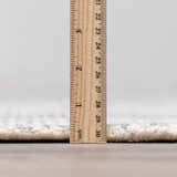 Close-up of the Orcas Hand Tufted Wool-Blend Rug in Slate, showing the pile height with a ruler. Cream and blue tones. Pile