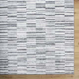 Close-up of Bronco Broken Striped Area Rug. Contemporary design with black, charcoal, gray, and ivory stripes. Corner