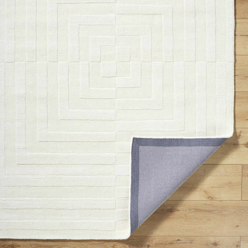 Close-up of the cream Armina Area Rug. Features a geometric, maze-like pattern and hand-loomed wool texture. Fold