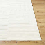 Close-up of the cream Armina Area Rug, a hand-loomed wool rug with a contemporary geometric pattern on a wood floor. Front