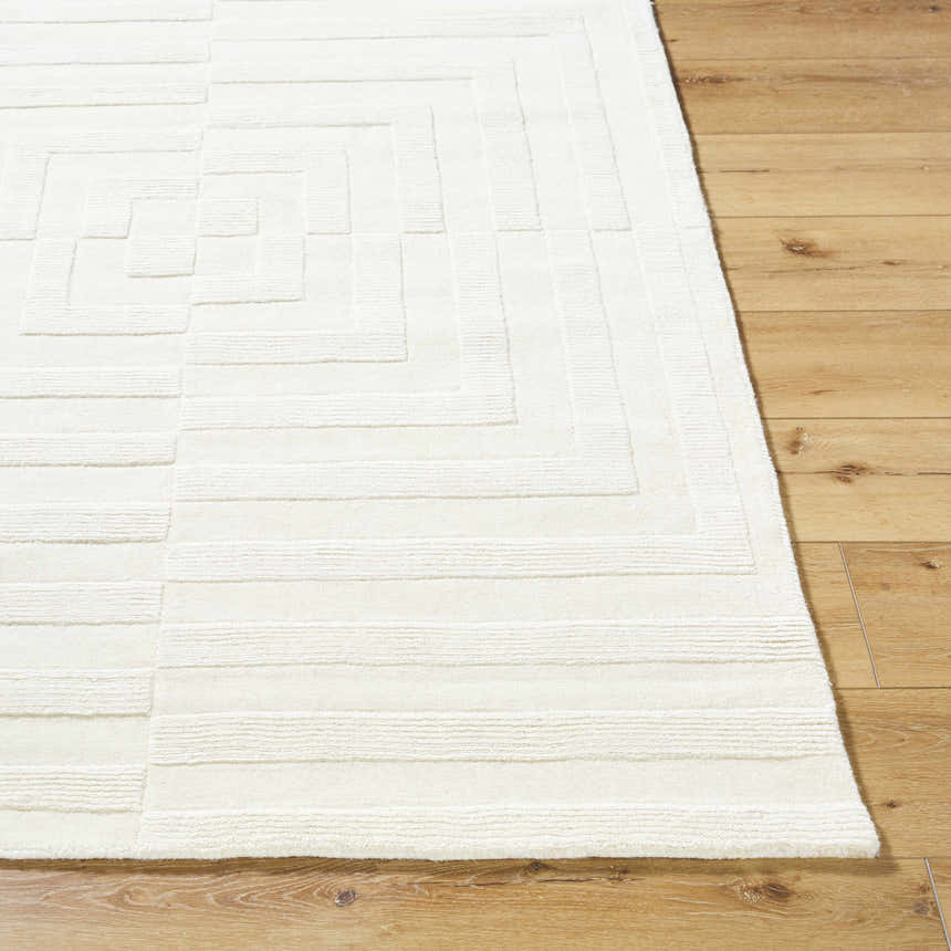 Close-up of the cream Armina Area Rug, a hand-loomed wool rug with a contemporary geometric pattern on a wood floor. Front