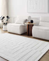Minimalist living room with cream Armina Area Rug, two chairs, wood side table, and neutral artwork. Roomscene-Rectangle