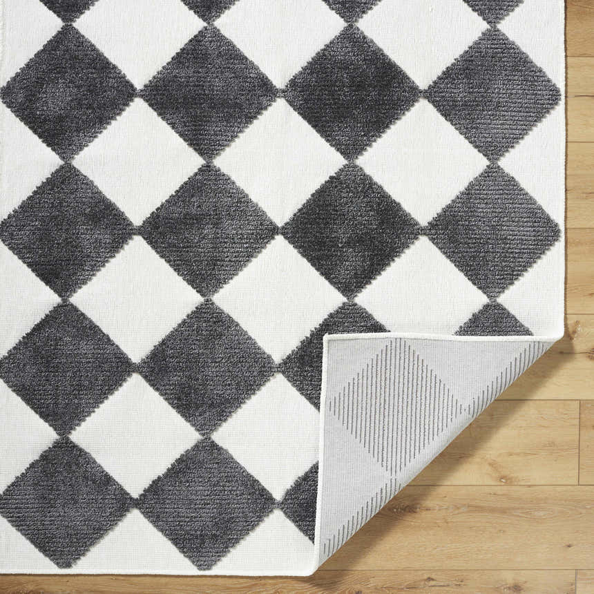 Close-up of Bosley Black Washable Area Rug with black and off-white diamond pattern and machine woven construction. Fold