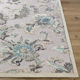 Close up of the Benita Area Rug showing aqua, cream, and light brown floral pattern and woven texture on wood floor. Front