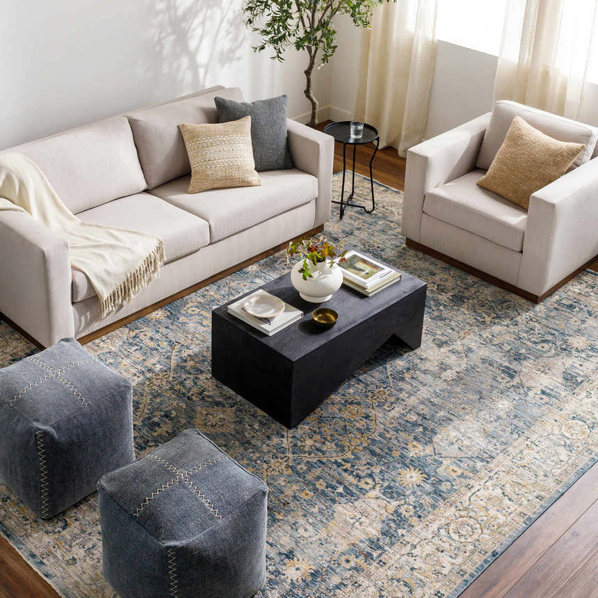 Living room scene with a Barcelona Luxe Performance Rug in blue and beige, sofa, chair, and ottomans. Roomscene-Rectangle