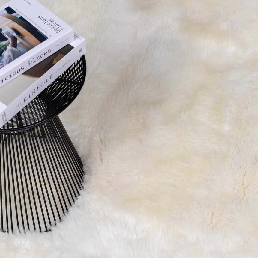 Close-up of a Premium White Soft Sheepskin Rug with a black wire side table and books on top. Styleshot